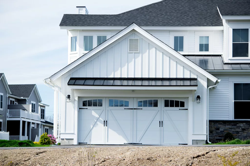 A two-story house with a fresh coat of white exterior paint and two garages