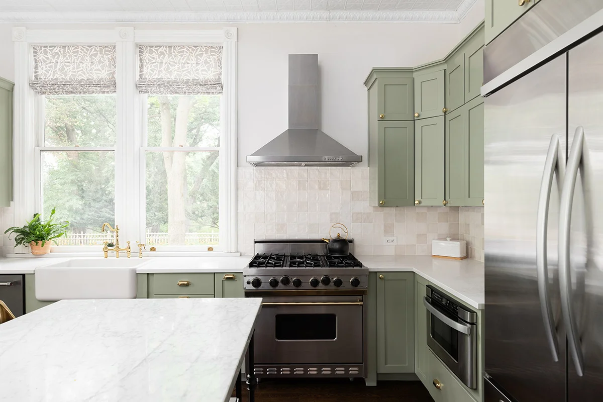 A modern kitchen with white countertops and newly painted sage green kitchen cabinets