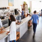 The interior of a busy coffee shop with newly painted white walls, showing the concept of minimizing business disruption during commercial painting