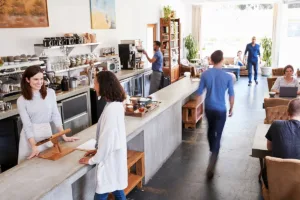 The interior of a busy coffee shop with newly painted white walls, showing the concept of minimizing business disruption during commercial painting