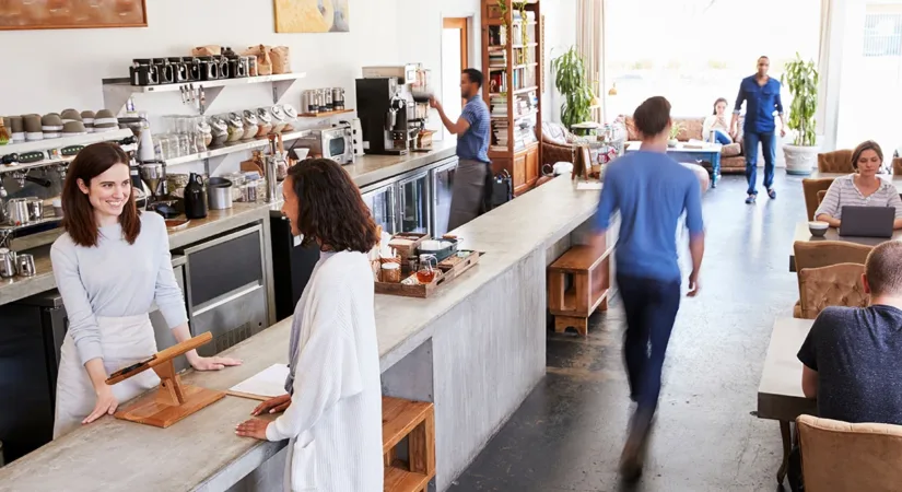 The interior of a busy coffee shop with newly painted white walls, showing the concept of minimizing business disruption during commercial painting