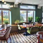 The interior of a restaurant with green paint color and checkered floors, showing the concept of choosing the best paint color for restaurants